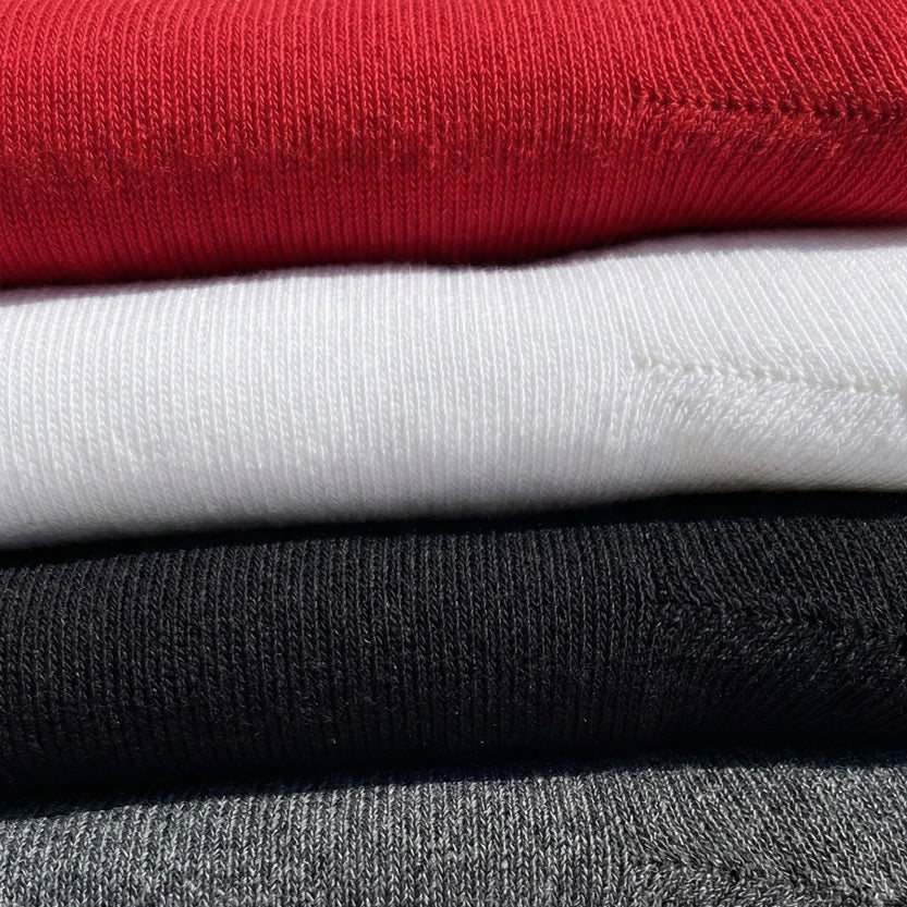 A close-up stack of folded knit garments in multiple colors, including red, white, black, and gray, showing the ribbed fabric texture.