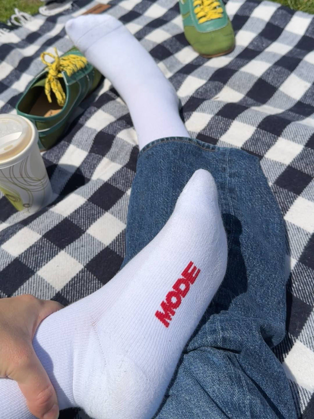 Person wearing white knee high compression socks with MODE logo on the bottom in red