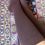 Brown knee high compression socks on a patterned rug