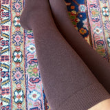 Brown knee high compression socks on a patterned rug