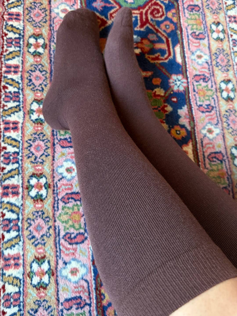 Brown knee high compression socks on a patterned rug