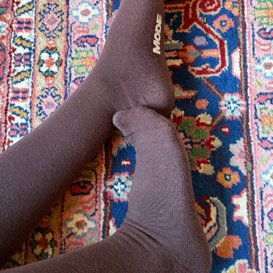 Brown knee high compression socks on a colorful patterned rug