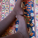 Brown knee high compression socks on a colorful patterned rug