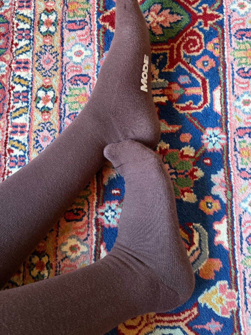 Brown knee high compression socks on a colorful patterned rug