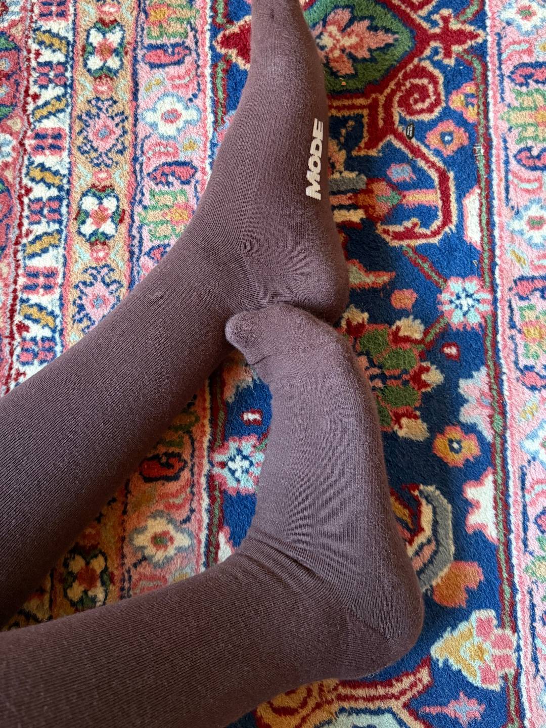 Brown knee high compression socks on a colorful patterned rug