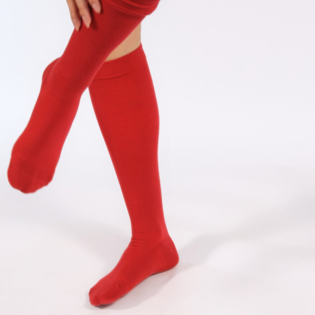 Red compression socks worn by a person on a white background