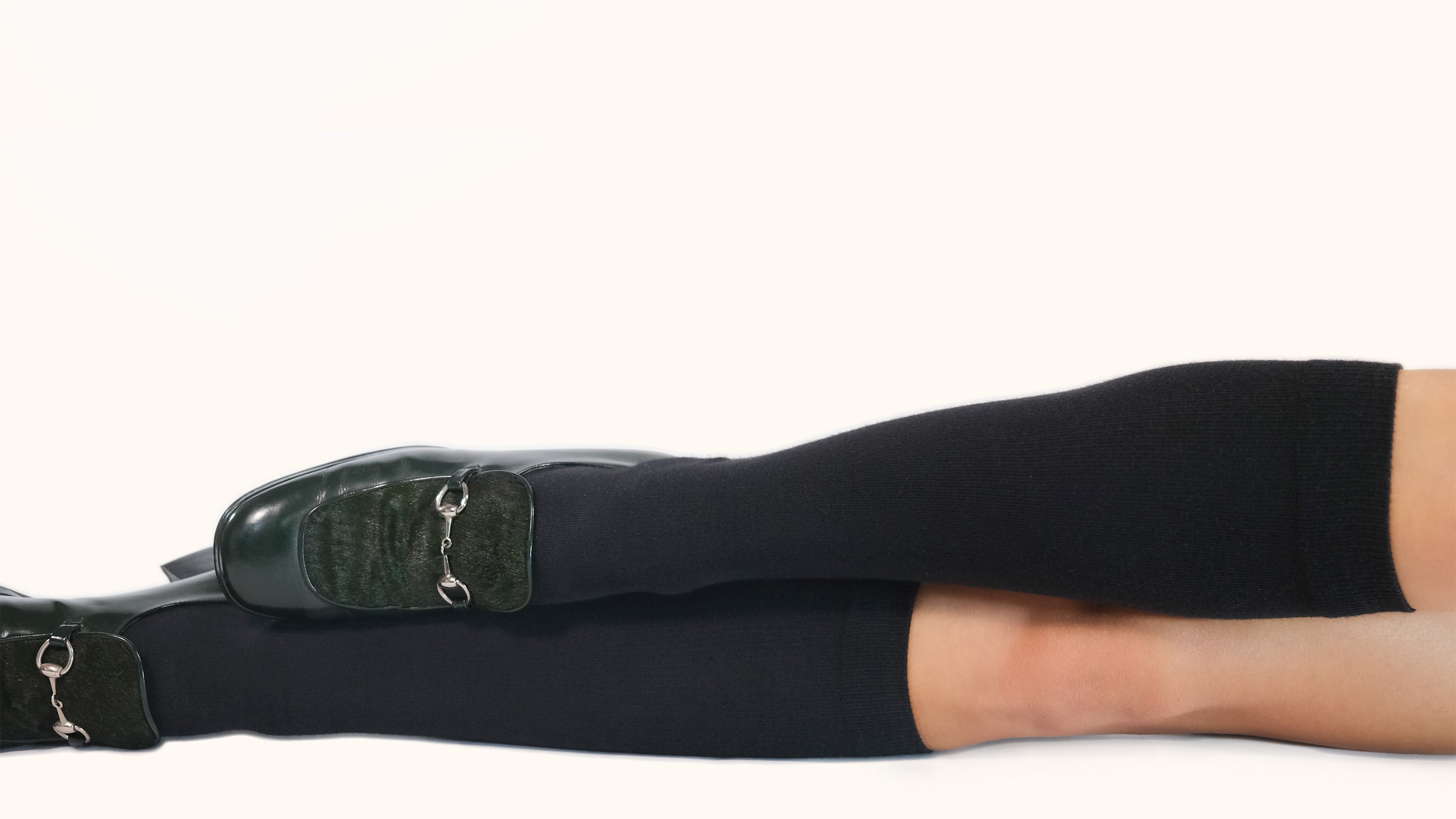 Black knee-high socks with green shoes on a white background