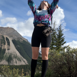 woman wearing black cotton knee high compression socks with black biker shorts taken in front of a mountain scene
