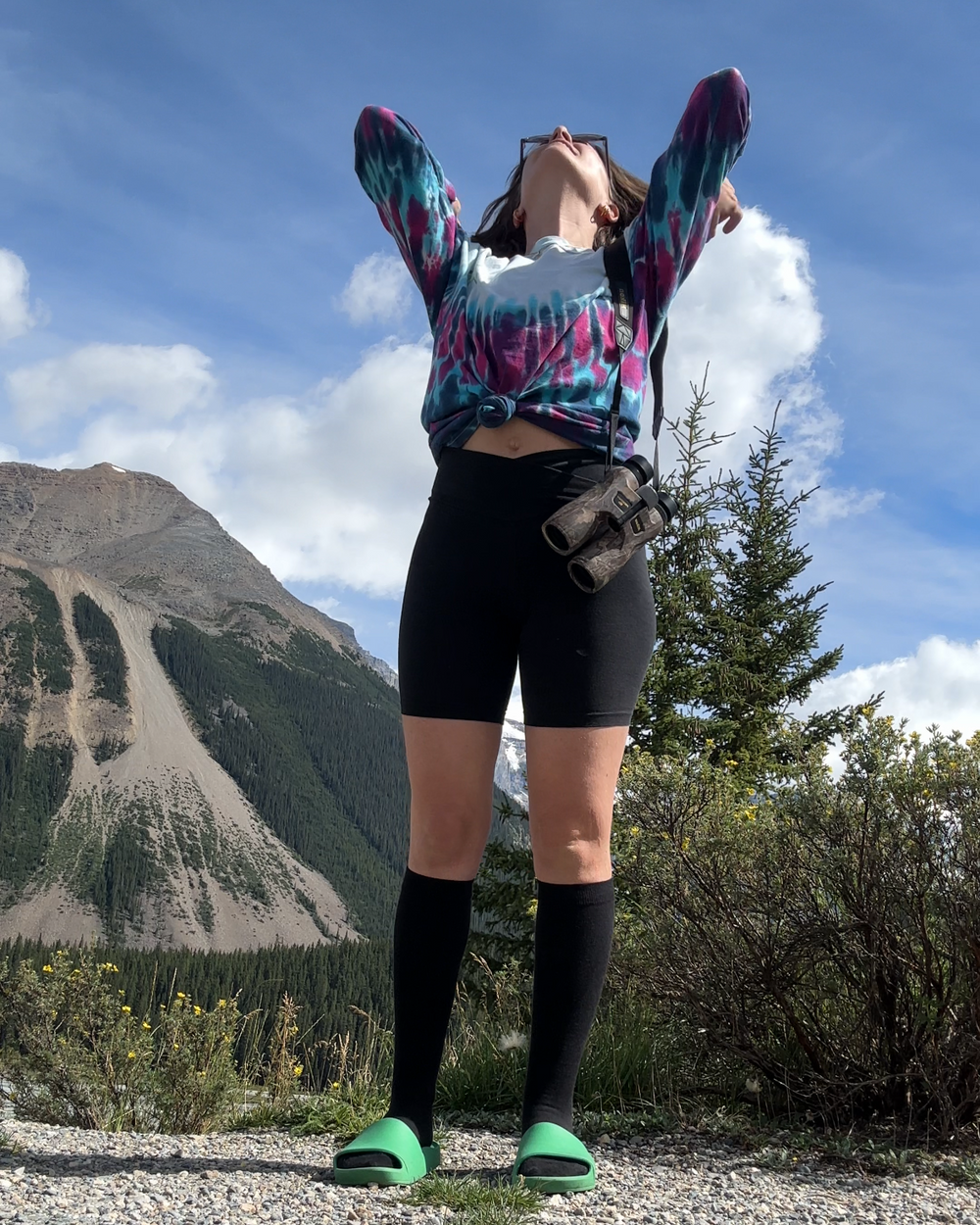 woman wearing black cotton knee high compression socks with black biker shorts taken in front of a mountain scene