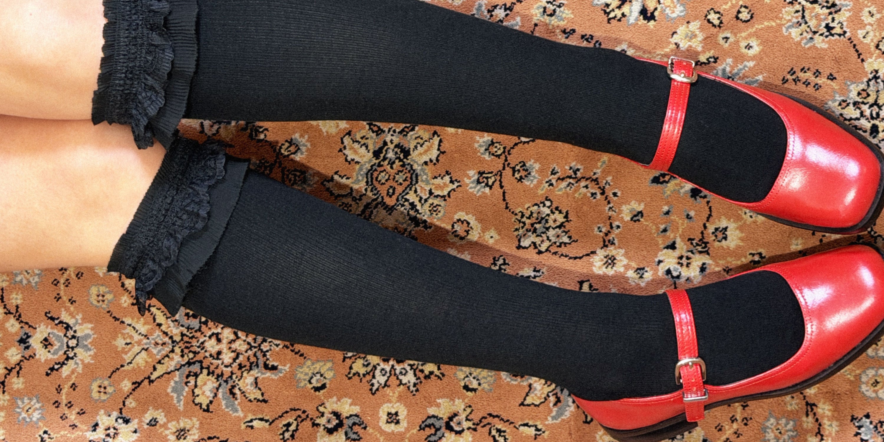 Red shoes with black socks on a patterned carpet
