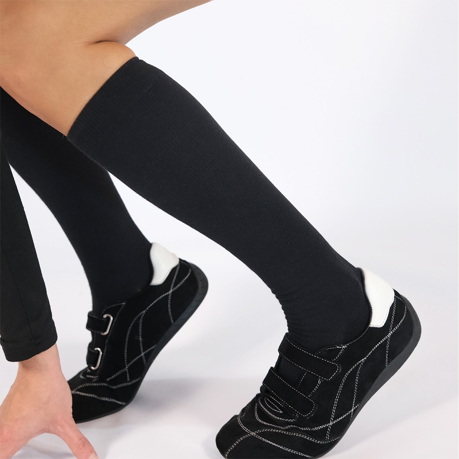 Black knee-high compression socks with black shoes on a white background