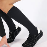 Black knee-high compression socks with black shoes on a white background