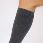 Close up detail of a gray knee-high compression sock on a white background