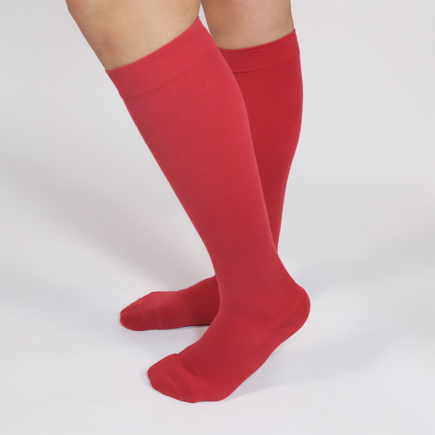 Person wearing red knee-high compression socks on a white background