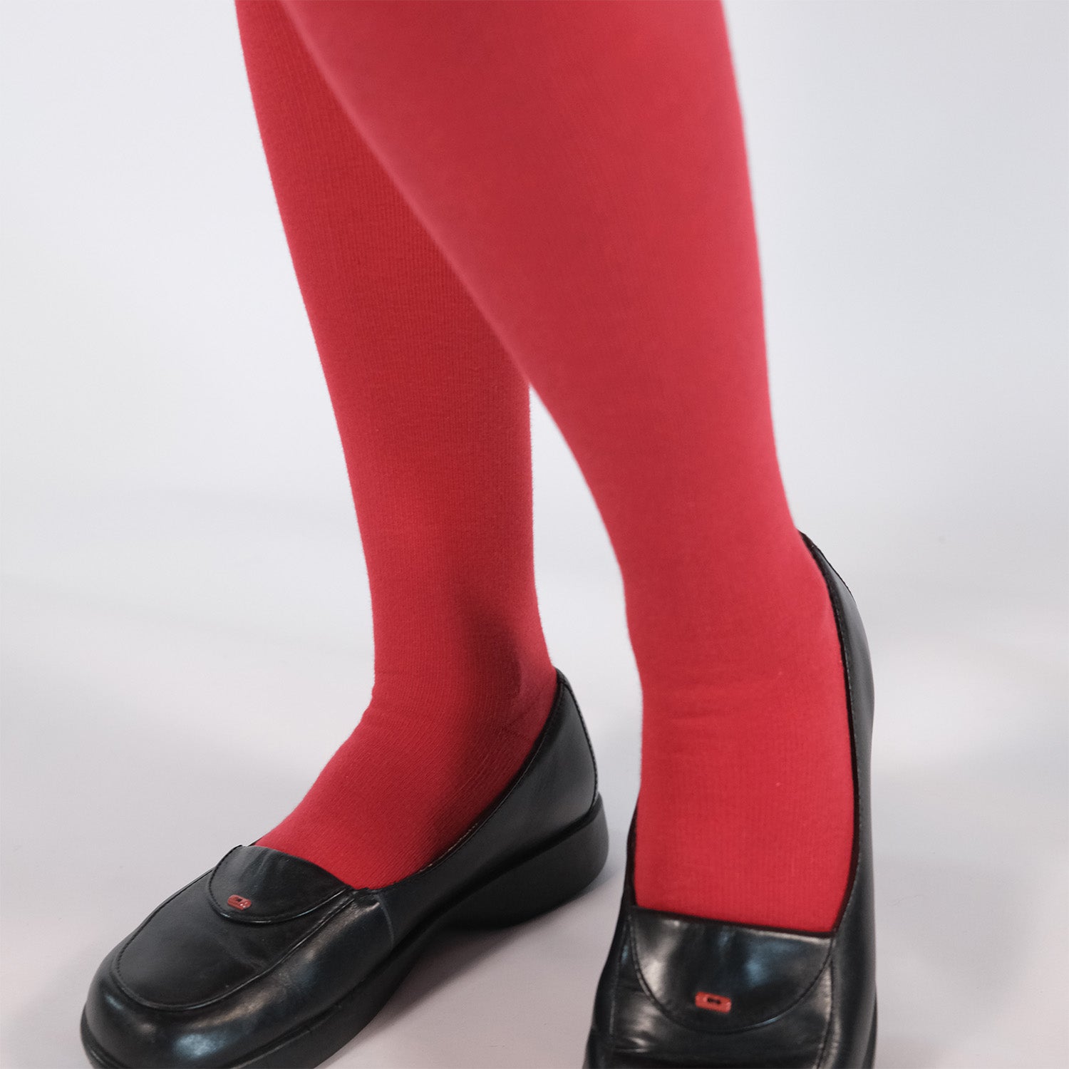 Person wearing red knee-high compression socks with black shoes on a white background